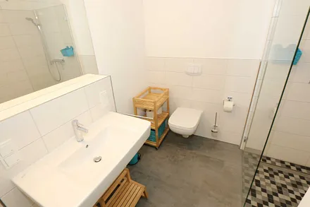 Badezimmer mit ebenerdiger Dusche, Waschplatz, WC, Handtuchheizkörper und Fön