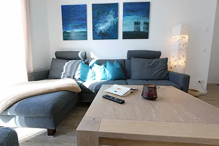 offener Wohnbereich mit gemütlicher Sitzecke, Couchtisch, Sessel, Leselampe, Smart-TV mit CD-Player, DAB Radio und Blu-Ray-Player