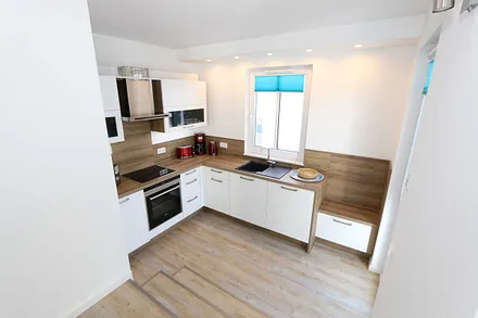 Küchenzeile mit Ceranfeld, Backofen, Geschirrspüler, Mikrowelle, Kühlschrank mit Gefrierfach, Kaffeemaschine, Wasserkocher, Toaster und diversen Küchenutensilien