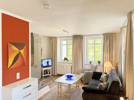 Wohnbereich mit Couchecke (Ausziehfunktion, Aufbettung 3./4. Person, 1,80 m x 2,00 m), Couchtisch, Leselampe und Sideboard mit Smart-TV sowie Radio + CD-Player