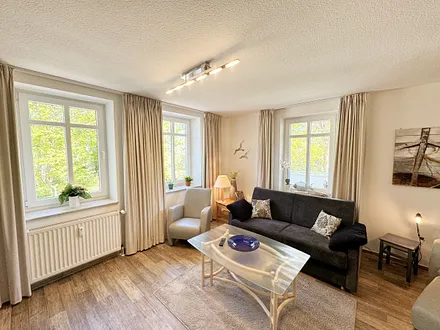 Wohnbereich mit Couchecke (Ausziehfunktion, Aufbettung 3./4. Person, 1,80 m x 2,00 m), Couchtisch, Leselampe und Sideboard mit Smart-TV sowie Radio + CD-Player