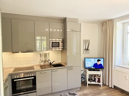 Küchenzeile mit Geschirrspüler, Backofen, 4-Zonen-Ceranfeld, Kühlschrank mit Eisfach, Kaffeemaschine, Mikrowelle, Toaster, Wasserkocher und diversen Küchenutensilien