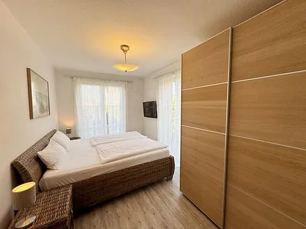 Schlafzimmer mit Doppelbett (2x 0,90 m x 2,00 m) in Komforthöhe (60cm) und zwei 7-Zonenkaltschaummatratzen,Nachttischablagen,Kleiderschrank,Wandspiegel und 40 Zoll LED - Flachbild TV