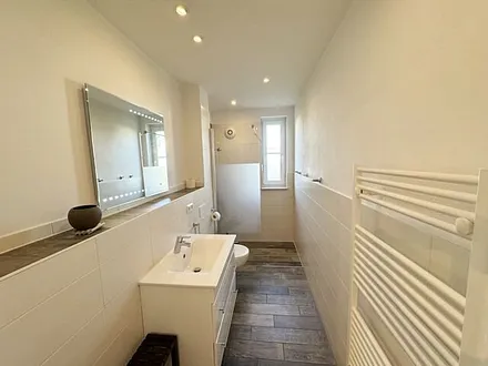 Tageslichtbadezimmer mit ebenerdiger Dusche, separater Lüftung, Fön, WC und Waschtisch mit Spiegelbeleuchtung