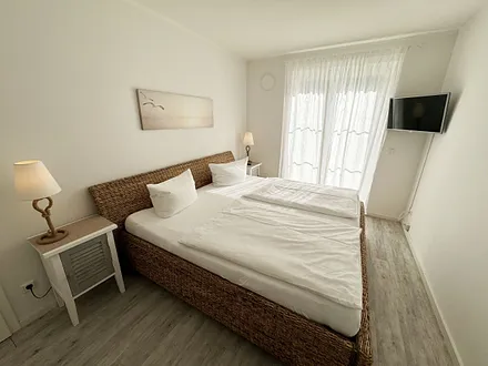 Schlafzimmer mit großem Doppelbett (2x 1,00 m x 2,00 m) in Komforthöhe, verstellbare Lattenroste, Nachttische, Kleiderschrank, Sekretär und Smart-TV mit Sat-Fernsehen