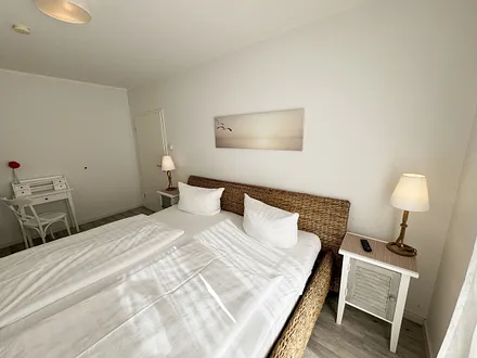 Schlafzimmer mit großem Doppelbett (2x 1,00 m x 2,00 m) in Komforthöhe, verstellbare Lattenroste, Nachttische, Kleiderschrank, Sekretär und Smart-TV mit Sat-Fernsehen