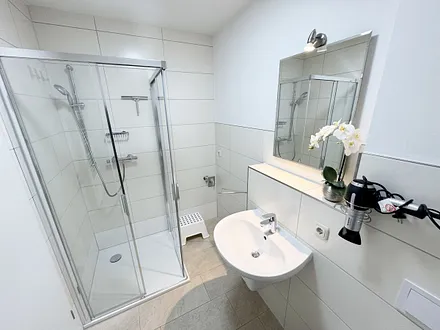 Badezimmer mit ebenerdiger Dusche und Waschbecken