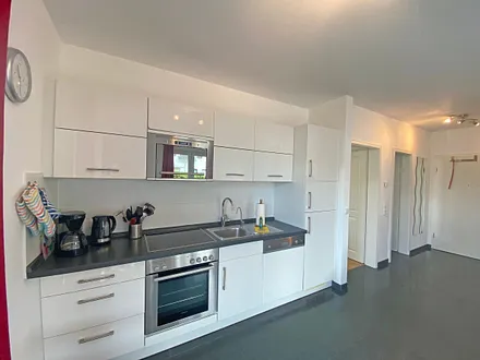 Küchenzeile mit Cerankochfeld, Backofen, Mikrowelle, Geschirrspüler, Kühlschrank mit Gefrierfach, Kaffeemaschine, Wasserkocher, Toaster und anderen praktischen Küchenutensilien