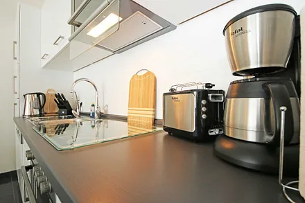 Küchenzeile mit Ceranfeld, Backofen, Geschirrspüler, Kühlschrank mit Gefriermöglichkeit, Mikrowelle, Kaffeemaschine, Wasserkocher, Toaster und diverse Küchenutensilien