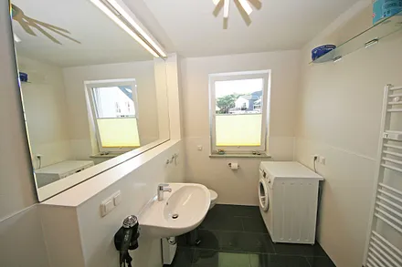 Badezimmer mit Dusche, Waschtisch, großem Spiegel und WC