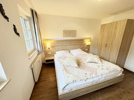 Schlafzimmer hell und modern eingerichtet mit Doppelbett, Komfortmatratzen (2x 0,90 m x 2,00 m), Nachttischkonsolen, Kleiderschrank und Verdunklungsgardinen