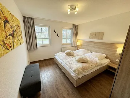 Schlafzimmer hell und modern eingerichtet mit Doppelbett, Komfortmatratzen (2x 0,90 m x 2,00 m), Nachttischkonsolen, Kleiderschrank und Verdunklungsgardinen