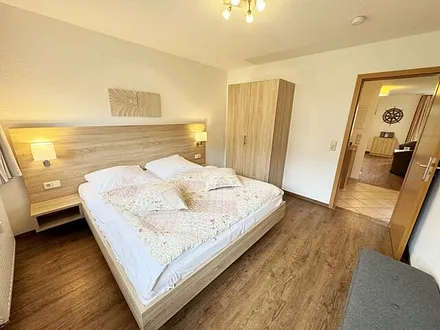 Schlafzimmer hell und modern eingerichtet mit Doppelbett, Komfortmatratzen (2x 0,90 m x 2,00 m), Nachttischkonsolen, Kleiderschrank und Verdunklungsgardinen
