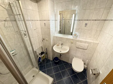 Badezimmer mit Dusche, Waschtisch, Fön und WC 