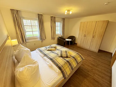 Schlafzimmer hell und modern eingerichtet mit Doppelbett, Komfortmatratzen (2x 0,90 m x 2,00 m), Nachttischkonsolen, Kleiderschrank und Verdunklungsgardinen