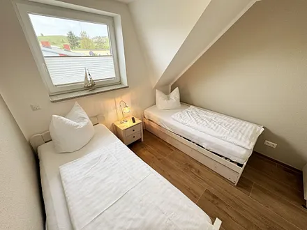 Schlafzimmer mit Einzelbett und einem Tandembett (Einzelbett mit Ausziehfunktion, je 0,90 m x 2,00 m) und einer Kommode 