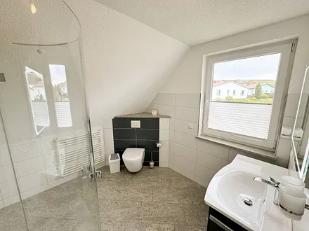 großzügiges Badezimmer mit Glasrunddusche, Handtuchtrockner, Fön, Waschbecken und WC