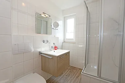 gefliestes Tageslichtbad mit Waschtisch, Fön, Kosmetikspiegel, WC und Dusche