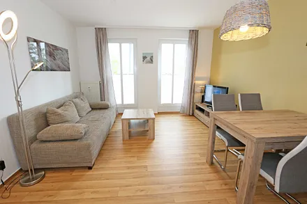 Wohnbereich mit hochwertiger Schlafcouch (1,60 m x 2,00 m, Aufbettungsmöglichkeit für 3/4 Person), Couchtisch, Leselampe, Sideboard mit Smart-TV mit Sky