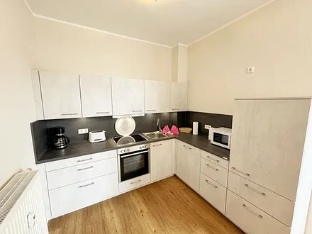 Küchenzeile mit Cerankochfeld, Backofen, Geschirrspüler, Kühlschrank, Gefrierfach, Kaffeemaschine, Mikrowelle, Wasserkocher, Toaster und diversen Küchenutensilien