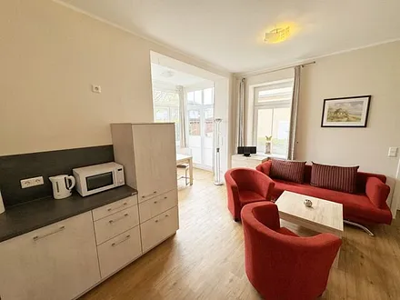 Küchenzeile mit Cerankochfeld, Backofen, Geschirrspüler, Kühlschrank, Gefrierfach, Kaffeemaschine, Mikrowelle, Wasserkocher, Toaster und diversen Küchenutensilien