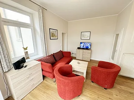 offener Wohnbereich mit Sofa, Sessel, Couchtisch und Sideboard, Flachbild-TV, Blu-Ray-Player und Mini-Stereo-Anlage mit USB-Anschluss