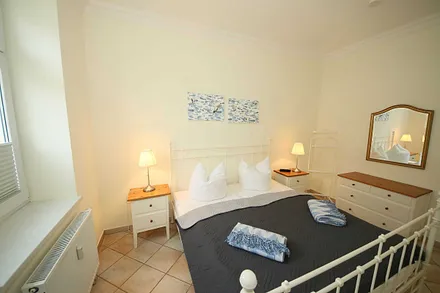 Schlafzimmer mit Doppelbett (1,80 m x 2,00 m), Nachttischablagen, geräumige Kommode und Wandspiegel