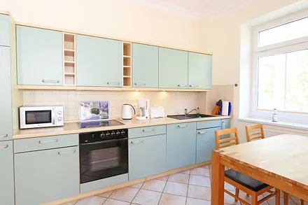 Küchenzeile mit Cerankochfeld, Backofen, Geschirrspüler, Mikrowelle, Kühlschrank, Gefrierfach, Kaffeemaschine, Wasserkocher, Toaster und diversen Küchenutensilien