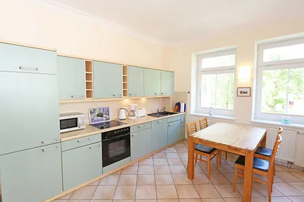 Küchenzeile mit Cerankochfeld, Backofen, Geschirrspüler, Mikrowelle, Kühlschrank, Gefrierfach, Kaffeemaschine, Wasserkocher, Toaster und diversen Küchenutensilien