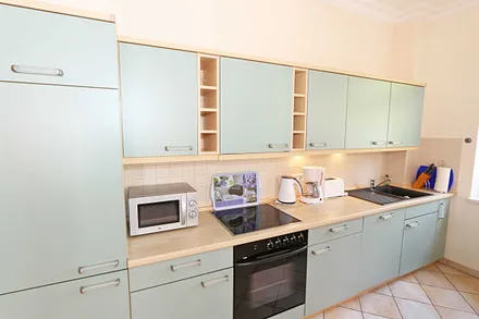 Küchenzeile mit Cerankochfeld, Backofen, Geschirrspüler, Mikrowelle, Kühlschrank, Gefrierfach, Kaffeemaschine, Wasserkocher, Toaster und diversen Küchenutensilien