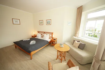 Schlafzimmer mit Doppelbett (1,80 m x 2,00 m), großem Kleiderschrank, Nachttischablagen, Kommode mit Smart-TV und komfortabler Leseecke mit kleiner Bücherauswahl