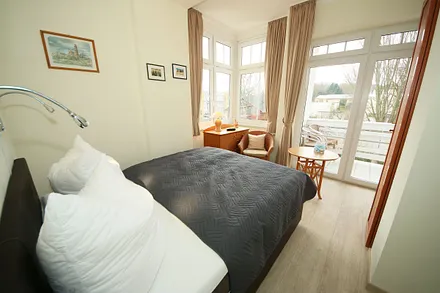 Schlafzimmer mit Boxspringbett (1,60 m x 2,00 m), kleinem Kleiderschrank, Kommode und Tisch mit 1 Sessel