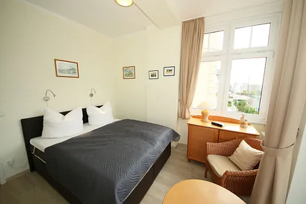 Schlafzimmer mit Boxspringbett (1,60 m x 2,00 m), kleinem Kleiderschrank, Kommode und Tisch mit 1 Sessel