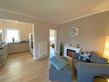 Wohnzimmer mit gemütlicher Couch, Couchtisch, Leselampe, Sessel, Hocker, Lowboard, Smart-TV, Blu-Ray Player, Teufel-Musikanlage mit Radio, DAB Radio, CD-Spieler, USB-Anschluss und Bluetooth