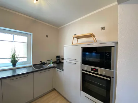 moderne Küchenzeile mit Geschirrspüler, Toaster, Wasserkocher, Kaffeemaschine, 4 Zonen-Kochfeld, Backofen, integrierte Mikrowelle, Kühl-Gefrierkombination und hochwertigen Granitarbeitsflächen