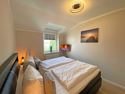 Schlafzimmer mit Boxspringbett (1,80 m x 2,00 m), Nachtischablagen, Kleiderschrank und Smart-TV 