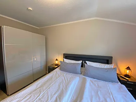 Schlafzimmer mit Boxspringbett (1,80 m x 2,00 m), Nachtischablagen, Kleiderschrank und Smart-TV 