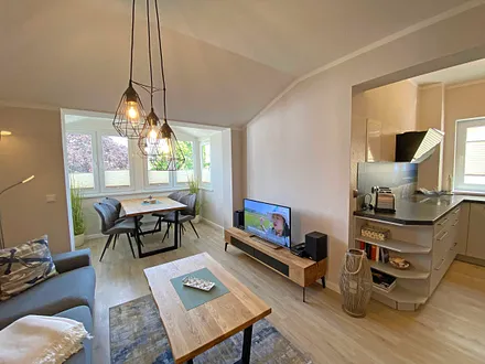 Wohnzimmer mit gemütlicher Couch, Couchtisch, Leselampe, Sessel, Hocker, Lowboard, Smart-TV, Blu-Ray Player, Teufel-Musikanlage mit Radio, DAB Radio, CD-Spieler, USB-Anschluss und Bluetooth