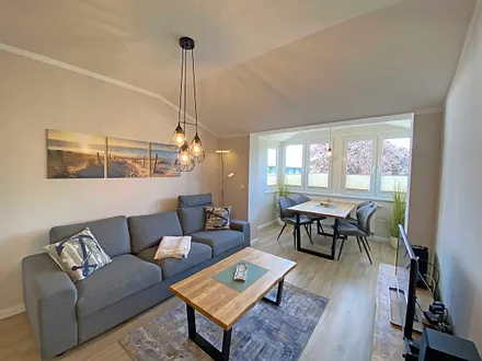 Wohnzimmer mit gemütlicher Couch, Couchtisch, Leselampe, Sessel, Hocker, Lowboard, Smart-TV, Blu-Ray Player, Teufel-Musikanlage mit Radio, DAB Radio, CD-Spieler, USB-Anschluss und Bluetooth