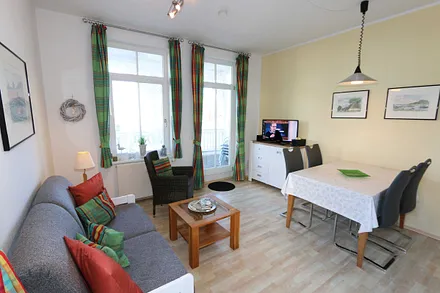 Wohnzimmer mit Sitzecke (Schlafcouch für 3./4. Person 1,50 m x 2,00 m), Smart-TV (81 cm), Leselampe, Blu-Ray-Player, DAB Radio und kleiner Anrichte