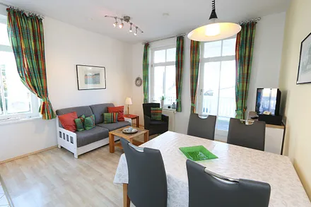 Wohnzimmer mit Sitzecke (Schlafcouch für 3./4. Person 1,50 m x 2,00 m), Smart-TV (81 cm), Leselampe, Blu-Ray-Player, DAB Radio und kleiner Anrichte