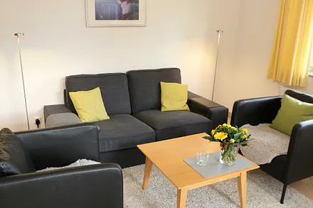 Wohnbereich mit Sofa, Sessel, Couchtisch, Vitrine, Leselampe, Flatscreen-TV mit DVD-Player, Stereoanlage mit CD und einer kleinen Auswahl an Gesellschaftsspielen 