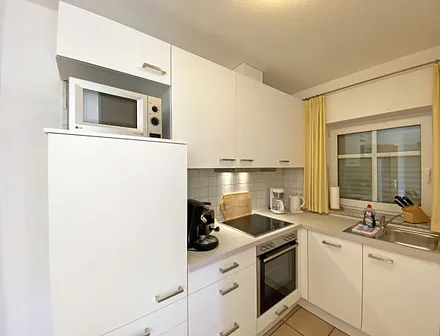 helle Küchenzeile mit Ceranfeld, Backofen, Geschirrspüler, Mikrowelle, Kühlschrank mit Gefrierfach, Kaffeemaschine, Senseo Kaffeeautomat, Toaster, Wasserkocher und diverse Küchenutensilien