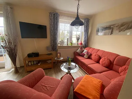 Wohnzimmer mit Fernseher und Sitzmöglichkeiten