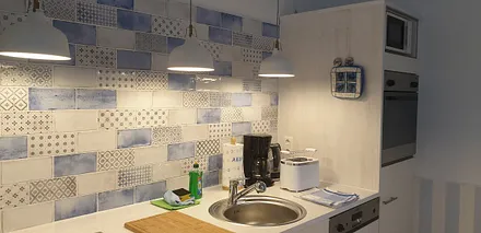 Küche mit Kaffeemaschine, Wasserkocher, Toaster, Mikrowelle, Herd, Backofen, Kühlschrank mit Gefrierfach