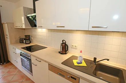 Küchenzeile mit Kühl-Gefrierkombination, Geschirrspüler, Backofen mit Ceran-Kochfeld, Kaffeemaschine, Toaster, Wasserkocher sowie diverse Küchenutensilien