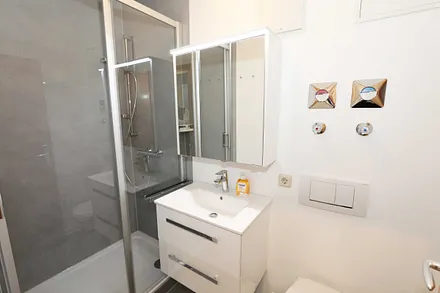 Badezimmer mit komfortabler Dusche (1,20 m x 0,80 m) mit Glasschiebetür, WC, Waschtisch, Kosmetikspiegel, Unterschrank, Spiegelschrank, Kosmetikspiegel sowie ein Fön