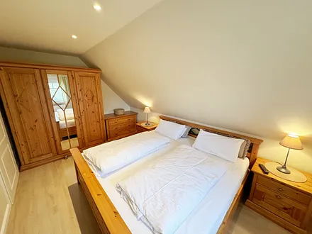 Schlafzimmer mit Doppelbett (2,00 m x 2,00 m), Nachttischkonsolen, Kleiderschrank und einer Kommode mit Flachbild-TV