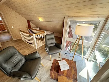 lichtdurchflutete Galerie mit bodentiefer Fensterfront, gemütliche Sitzgruppe (mit Blick in den Kiefernwald) und ein franzöisches Bett (1,40 m x 2,00 m unter einer Dachschräge)