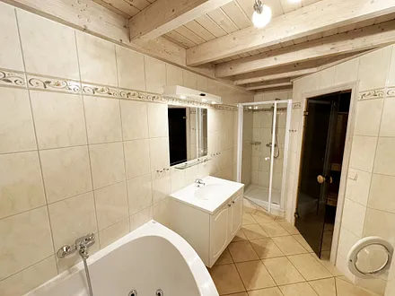 vollausgestattetes Badezimmer mit Dusche, Whirlpool-Badewanne, WC, Waschplatz, Fön, Kosmetikspiegel, Waschmaschine und Sauna